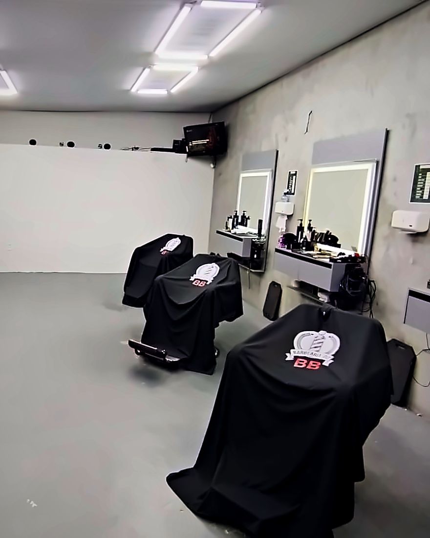 A cadeira da barbearia pronta, com a capa do brasão, num salão vazio
