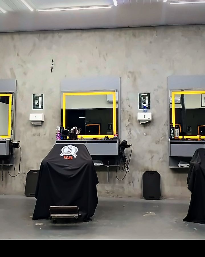 Uma das estações da barbearia, com o espelho de moldura amarela e a cadeira